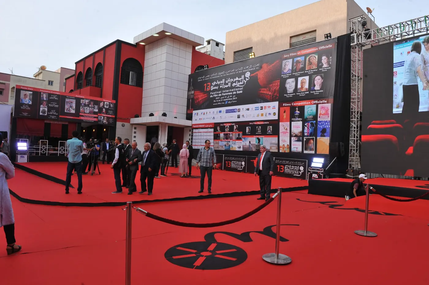 A red carpet and festival screens outside a red building for the International Women’s Film Festival.