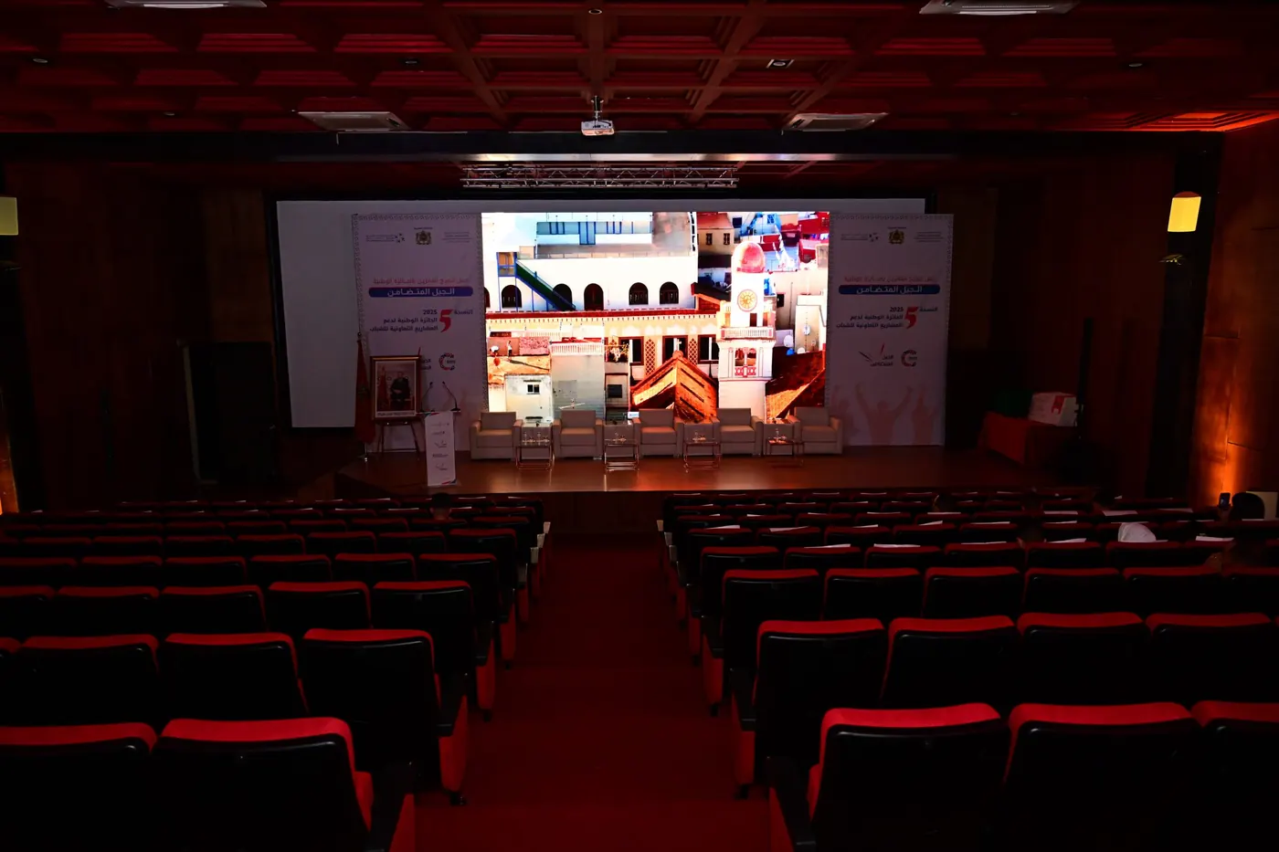 A theatre with red seats facing a projected screen for the ODCO national ceremony.