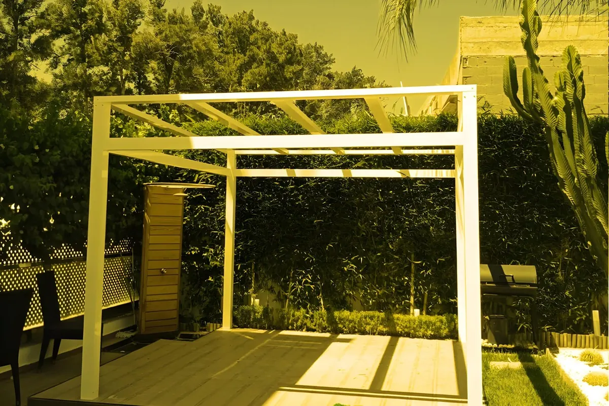 A white aluminium pergola on a wooden deck.