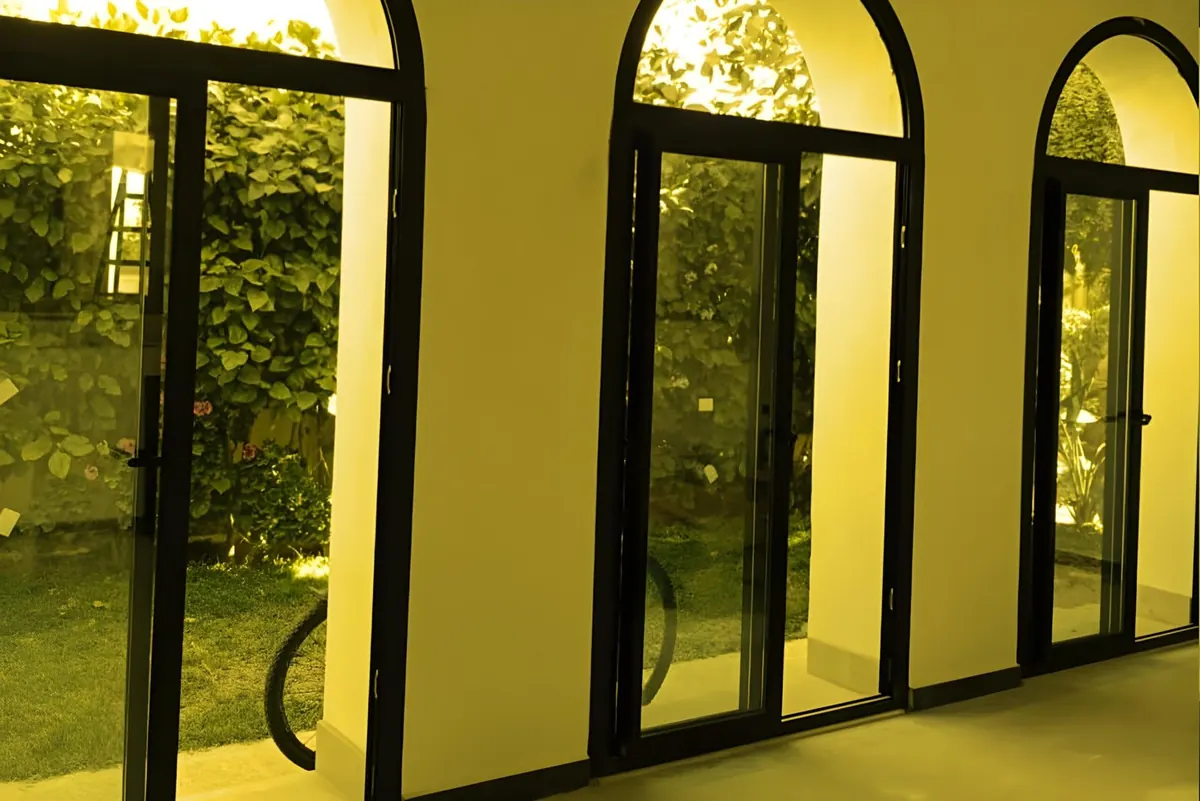 Arched aluminium windows and doors on a white facade.