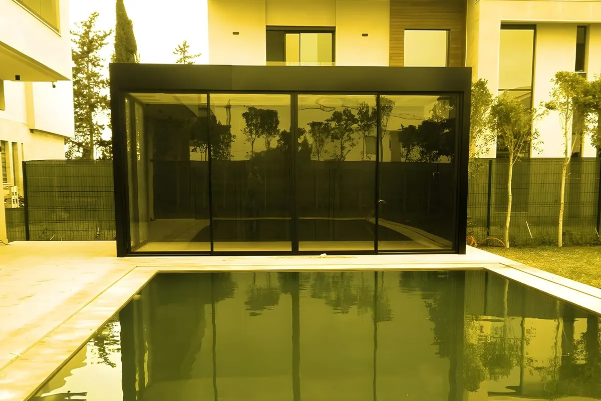 A glass room beside a swimming pool.