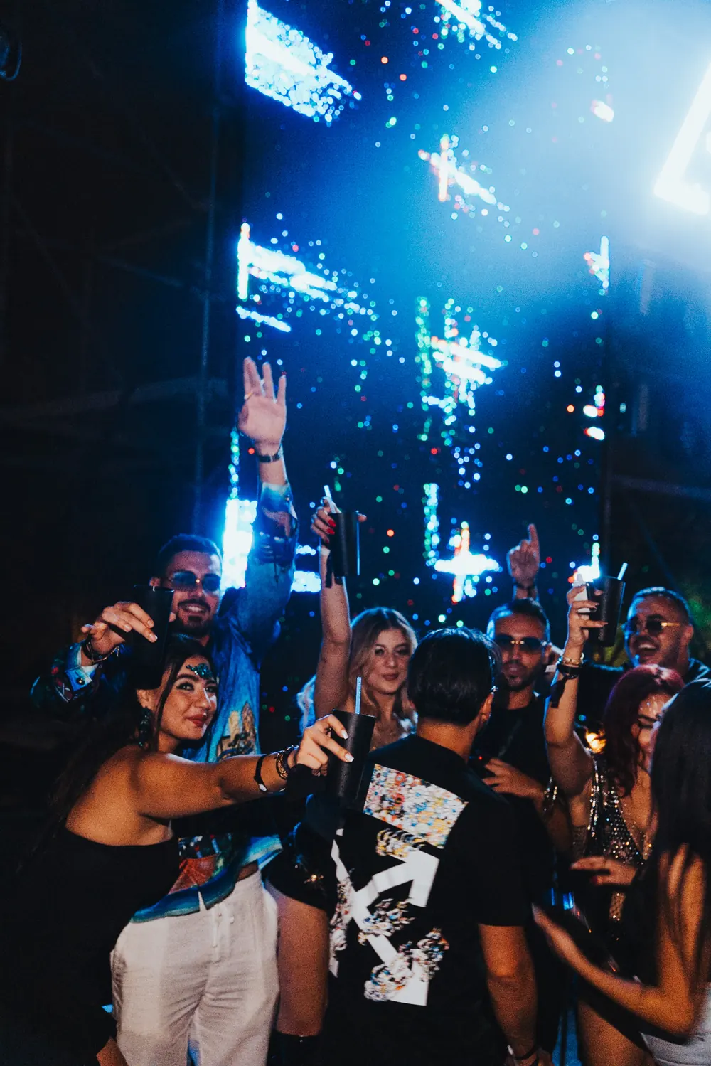 Crowd with hands up under blue light and the LED wall.