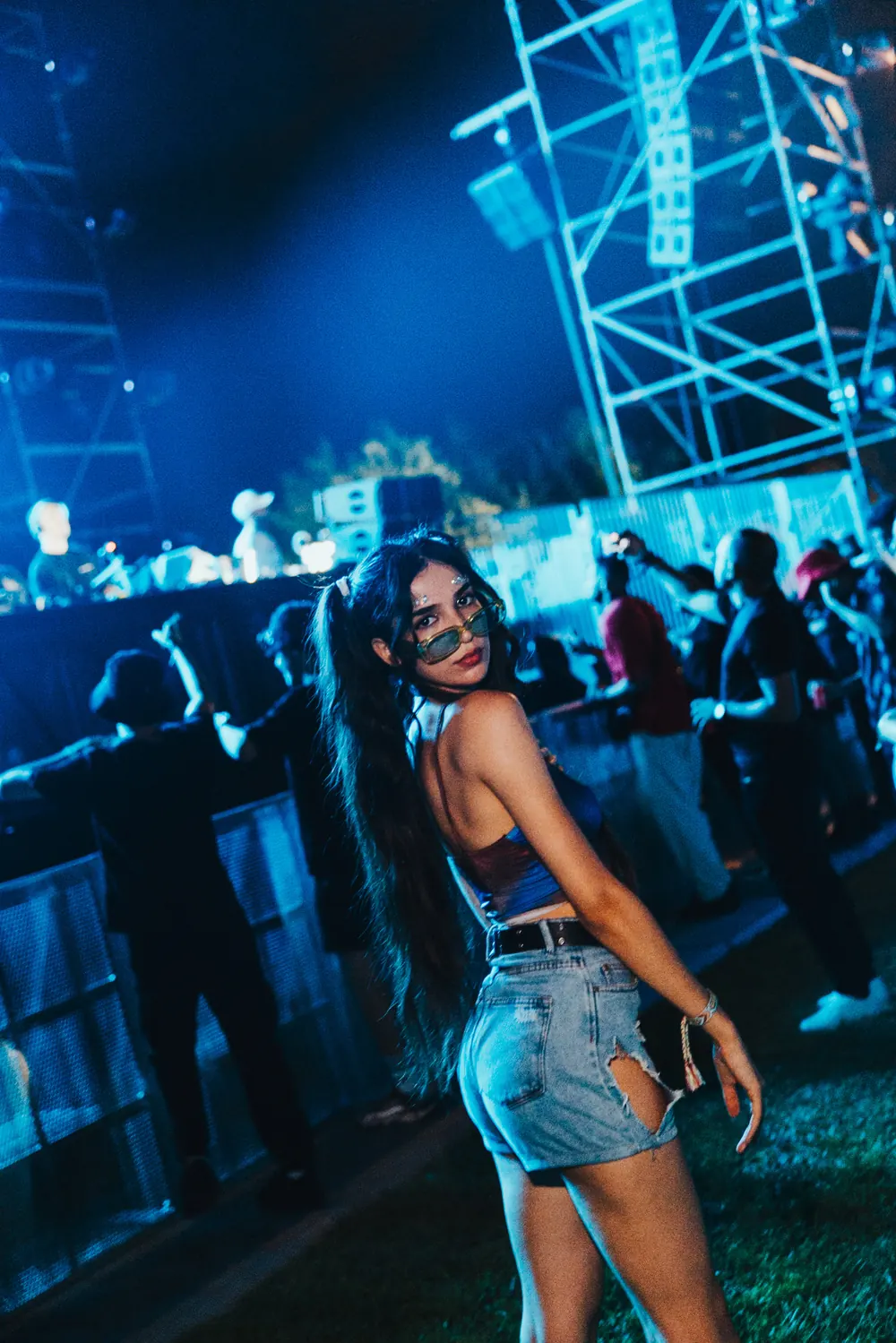 A guest turning to the camera at the barrier, the truss tower lit behind her.