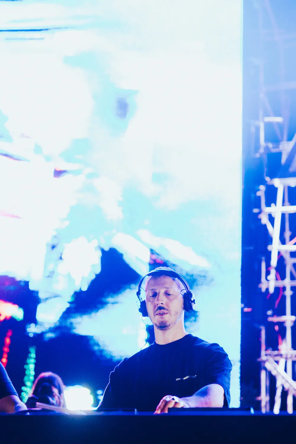 An artist with headphones in front of the bright LED wall.