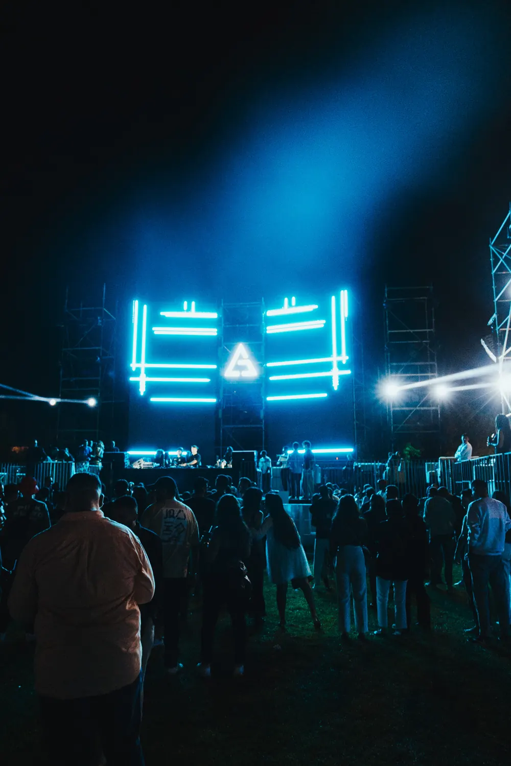 The main stage on the night: LED frames and the triangle glowing cyan above the crowd.