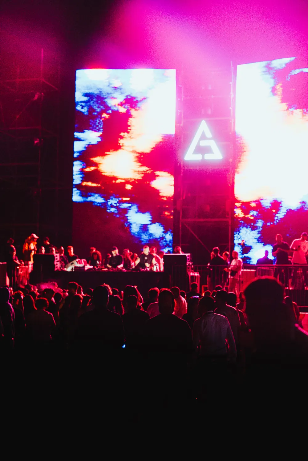 The LED screens flooded red and magenta behind the triangle.